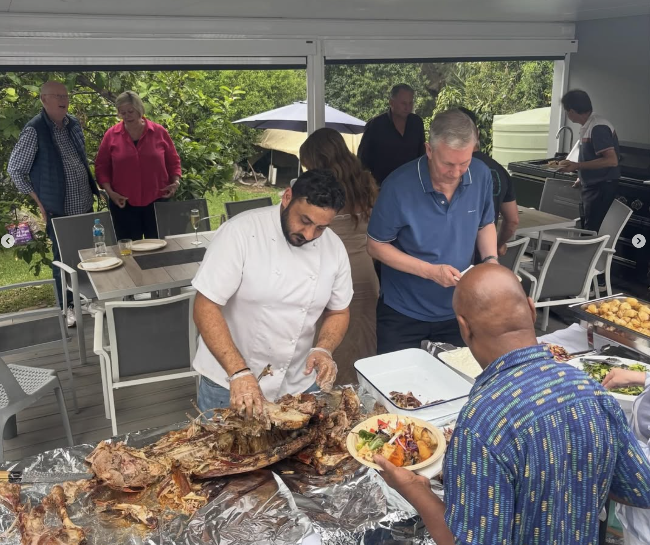Adamou serving freshly carved roast meat to guests at a gathering